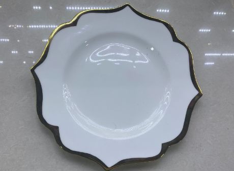 White plate with a wavy black and gold rim